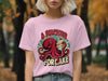 Octopus wearing a pink t-shirt, eating cake.