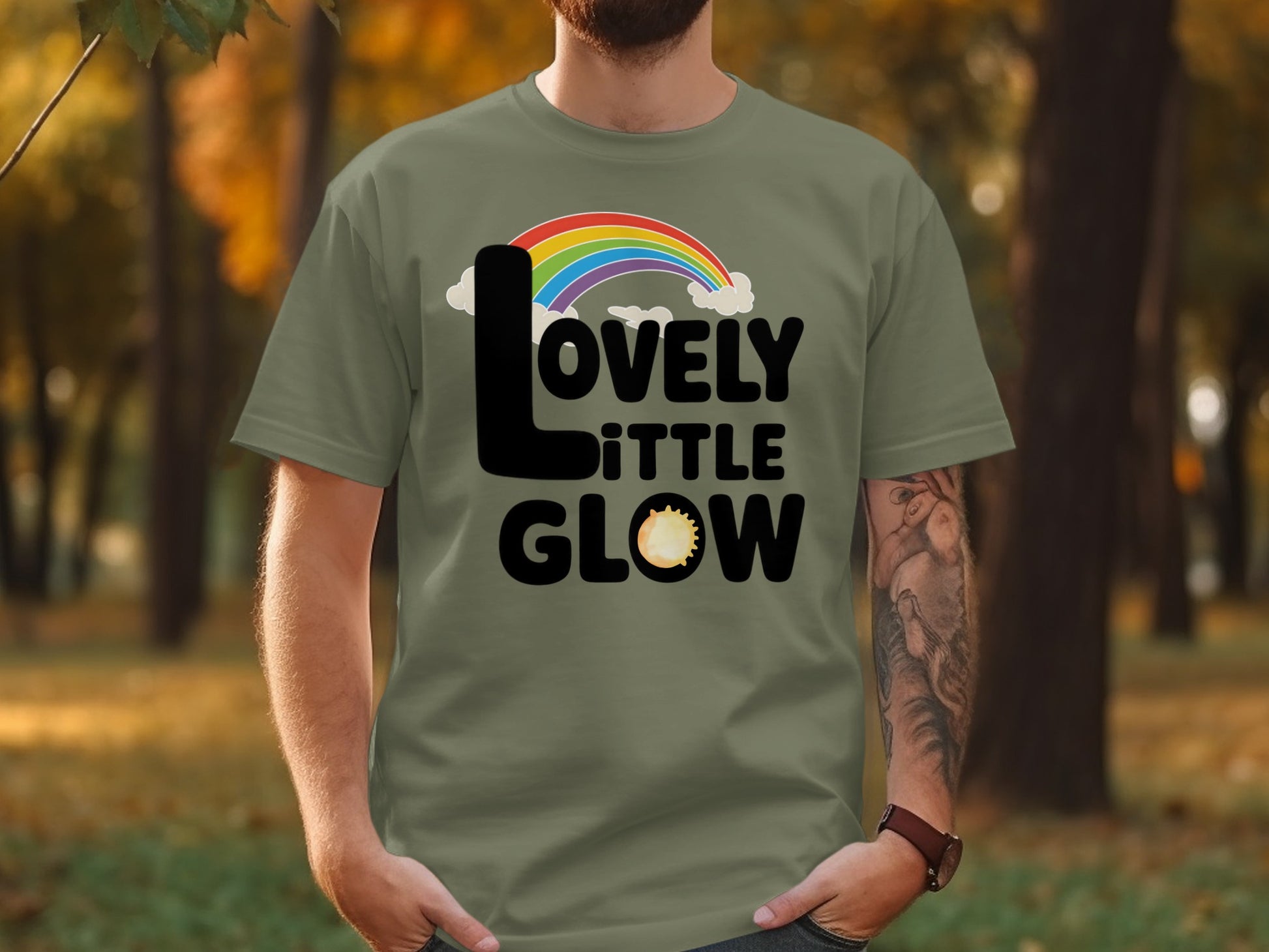 Green t-shirt with "Lovely Little Glow" text and rainbow, clouds, and sun graphic.