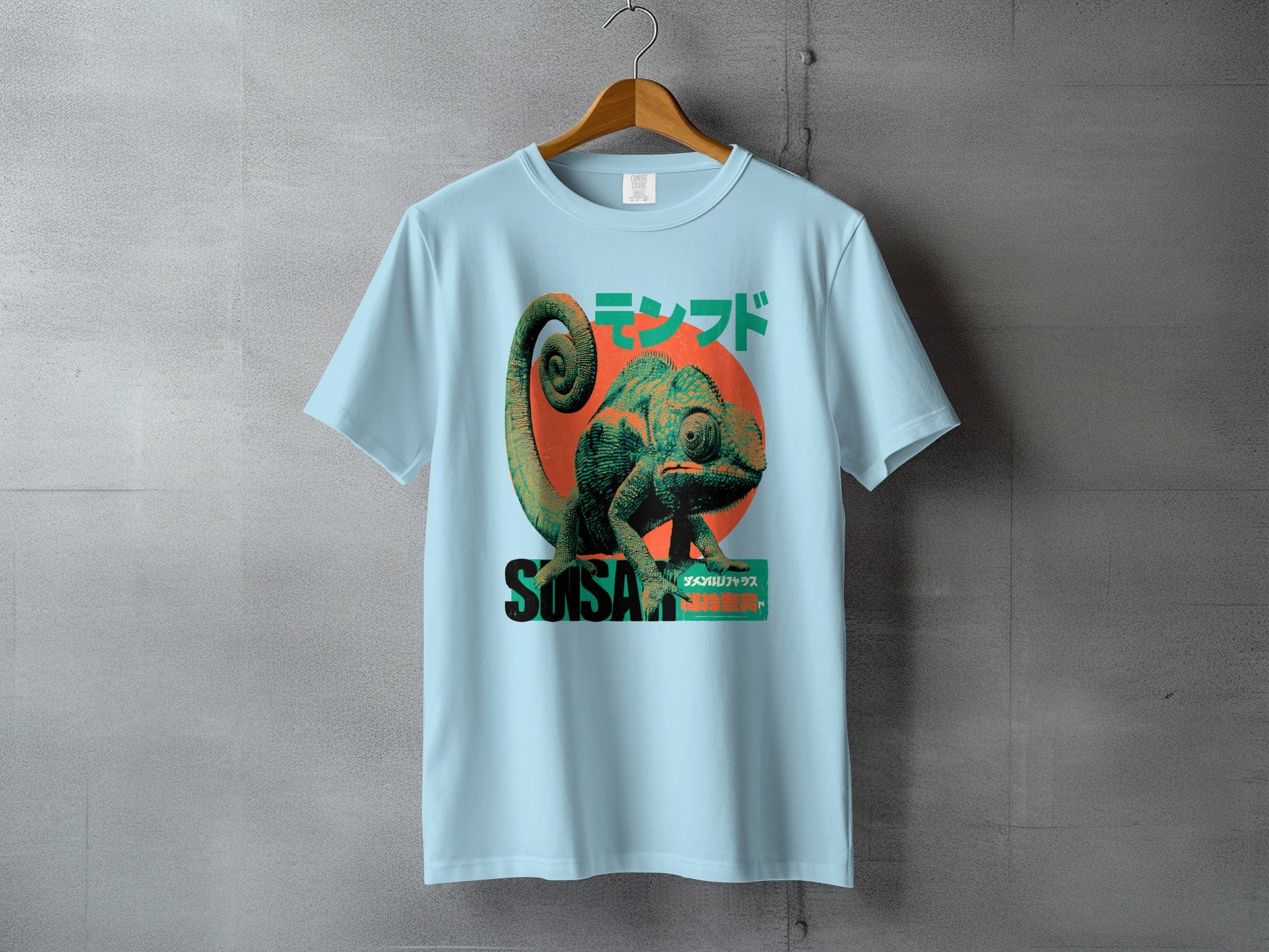 Light blue t-shirt with a stylized green chameleon and Japanese text.