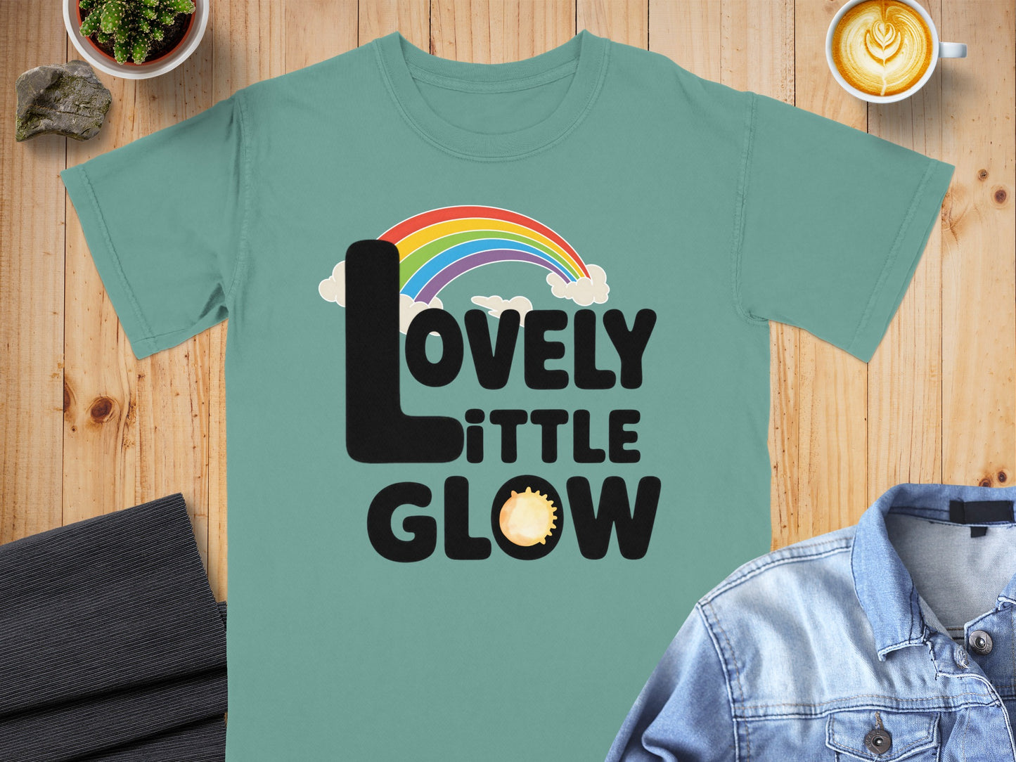 LOVELY LITTLE GLOW text with rainbow and sun graphic.