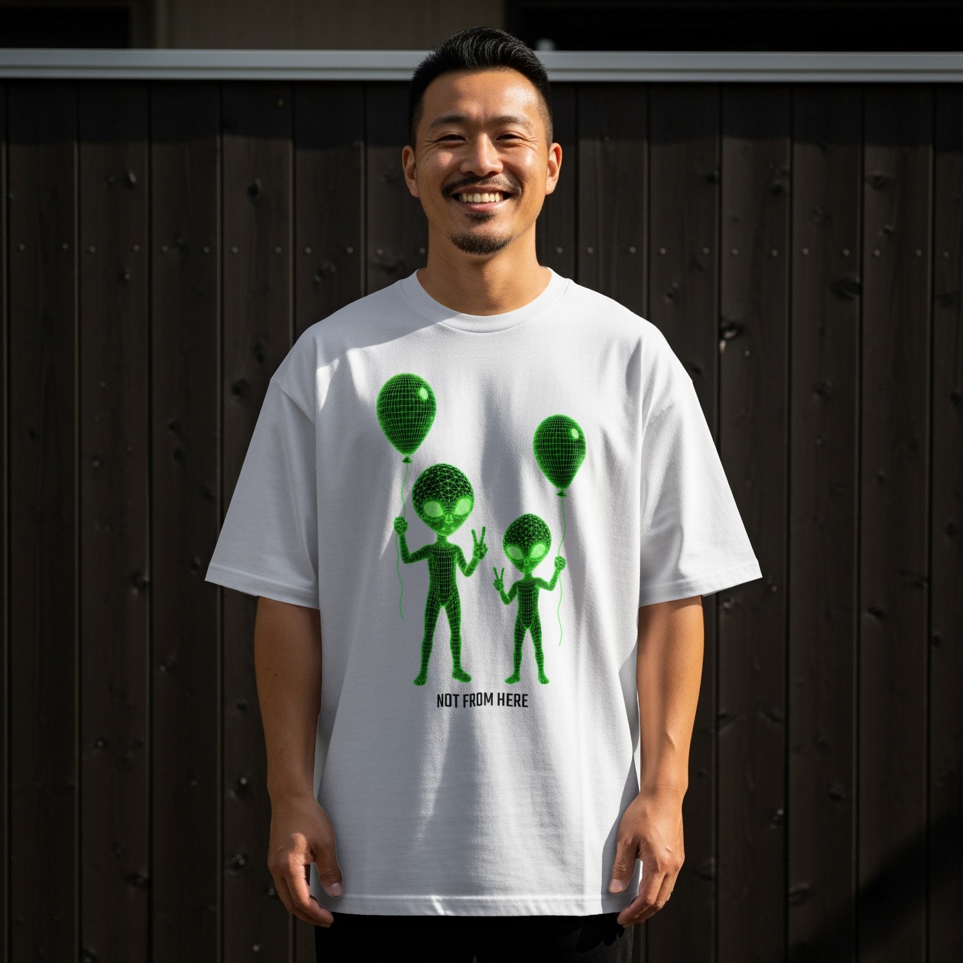 White t-shirt with green alien graphics and "NOT FROM HERE" text.