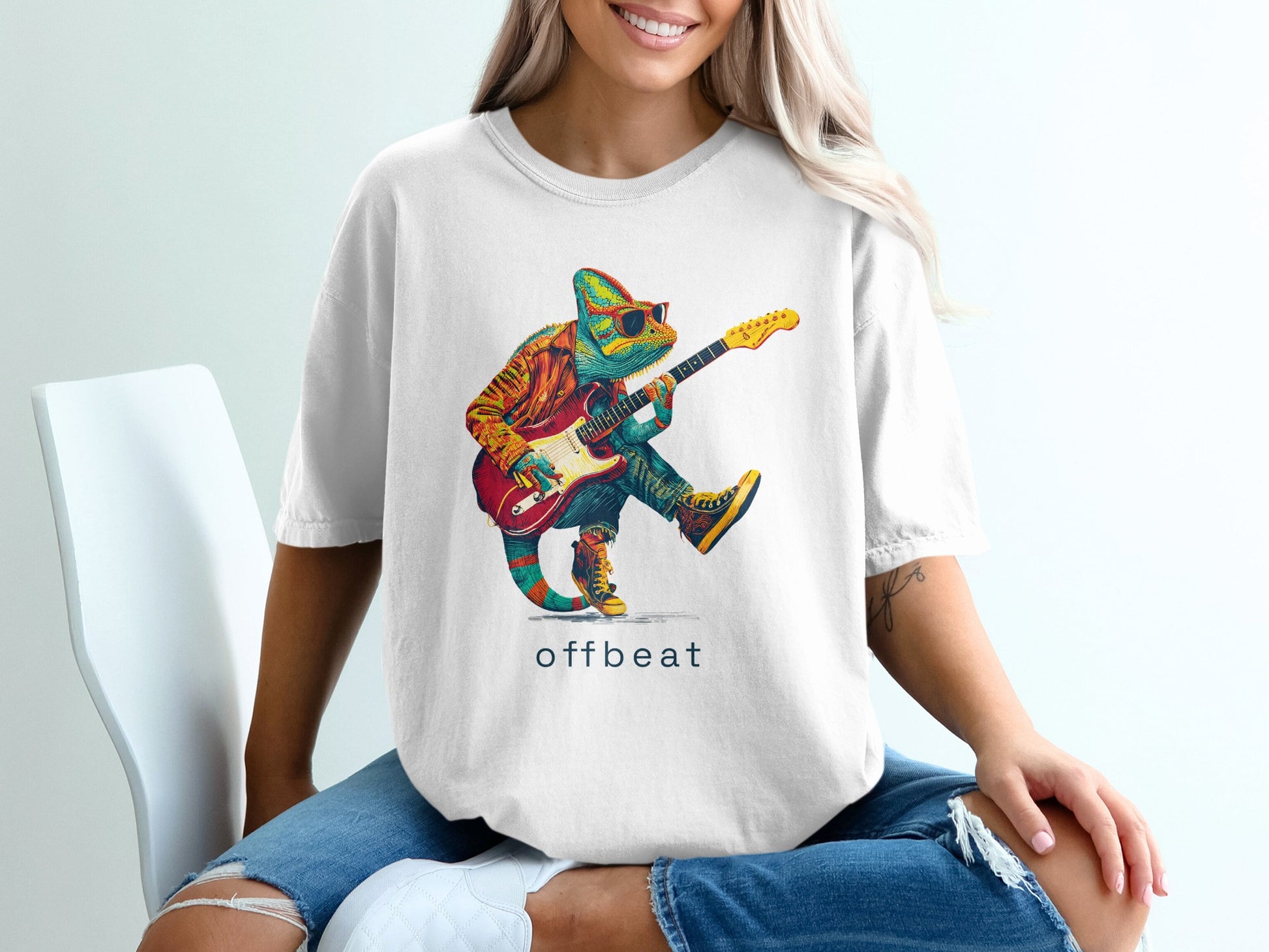 Chameleon in sunglasses plays a guitar on a white t-shirt.