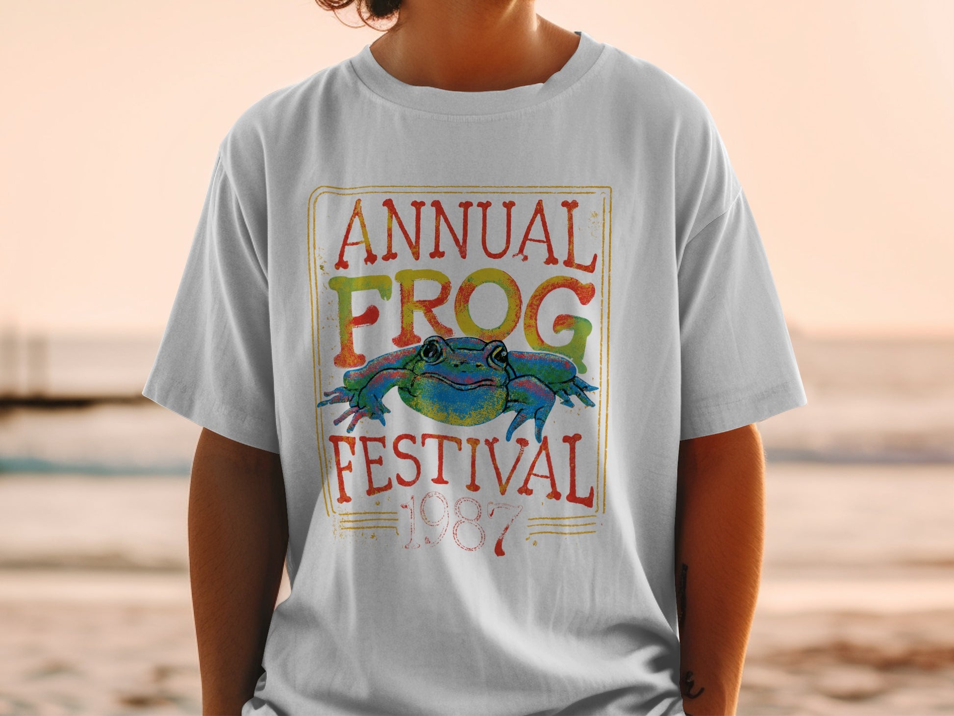 White t-shirt with "Annual Frog Festival 1987" and colorful frog graphic.