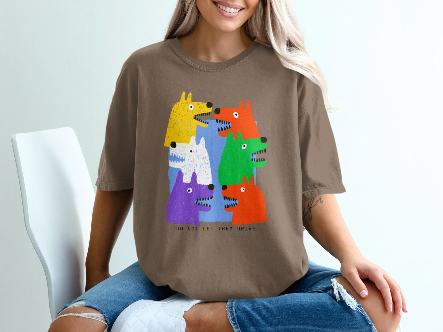 Brown t-shirt with a colorful graphic of cartoon dogs and text "DO NOT LET THEM DRIVE".
