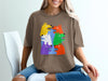 Brown t-shirt with a colorful graphic of cartoon dogs and text "DO NOT LET THEM DRIVE".