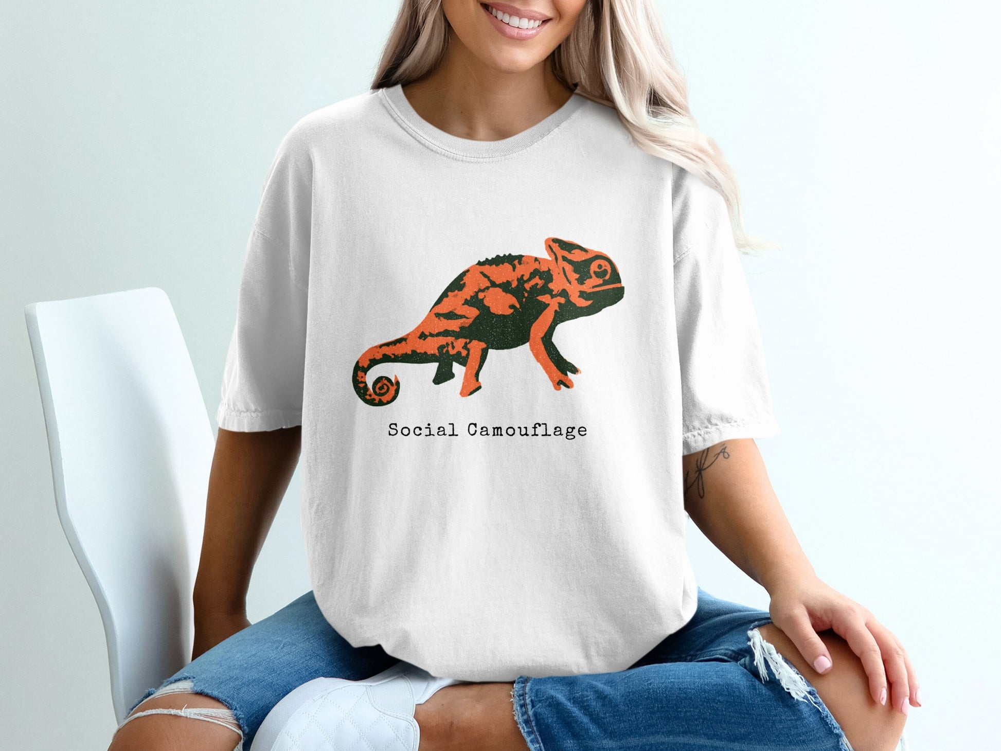 White t-shirt with an orange and black chameleon design and text.