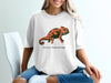 White t-shirt with an orange and black chameleon design and text.