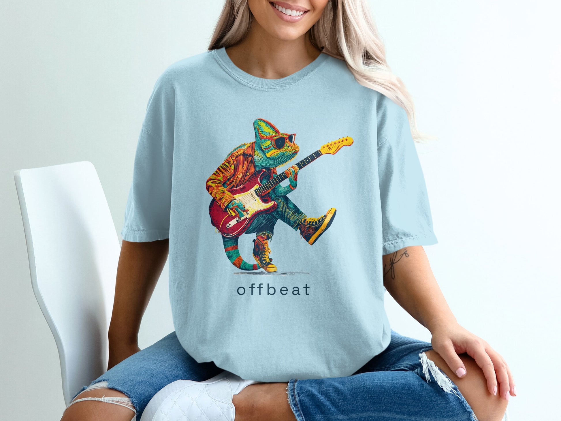 Chameleon wearing sunglasses plays electric guitar on light blue t-shirt.