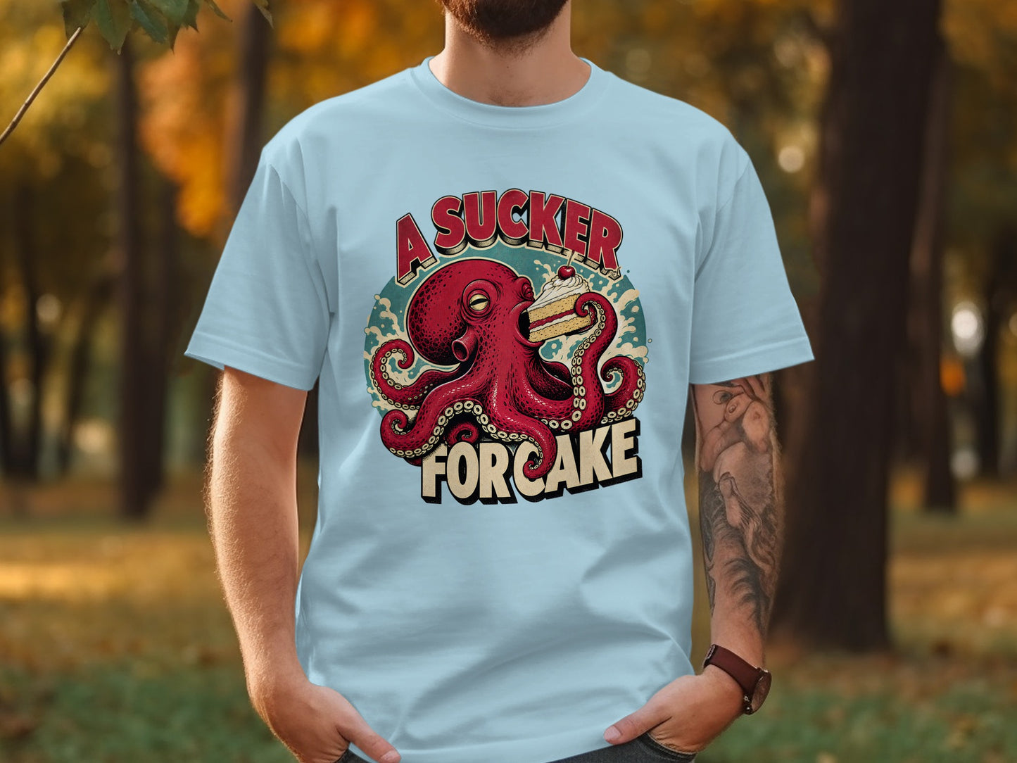 Octopus holding cake with "A Sucker For Cake" text on light blue t-shirt.
