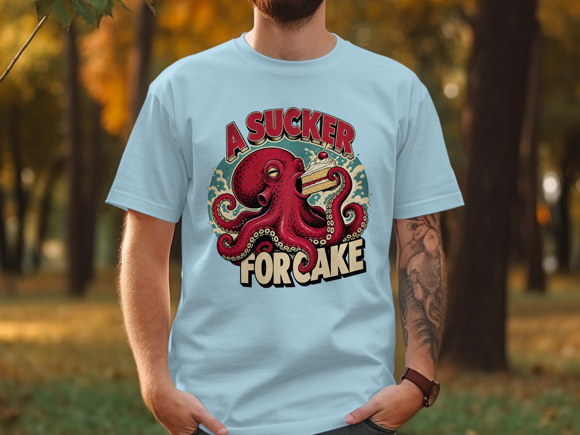 Octopus holding cake with "A Sucker For Cake" text on light blue t-shirt.