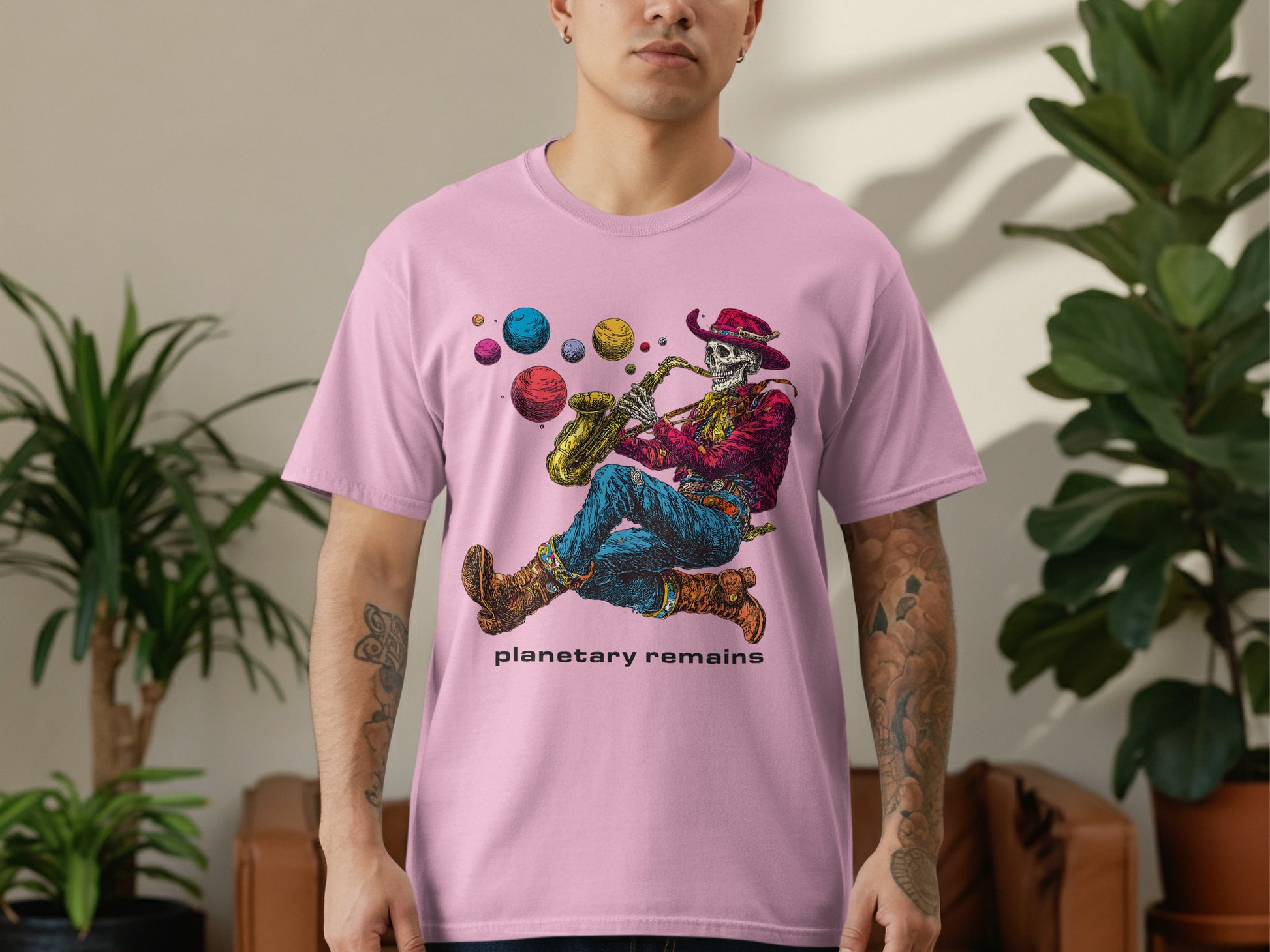 Pink t-shirt with skeleton playing saxophone surrounded by planets, text "PLANETARY REMAINS".