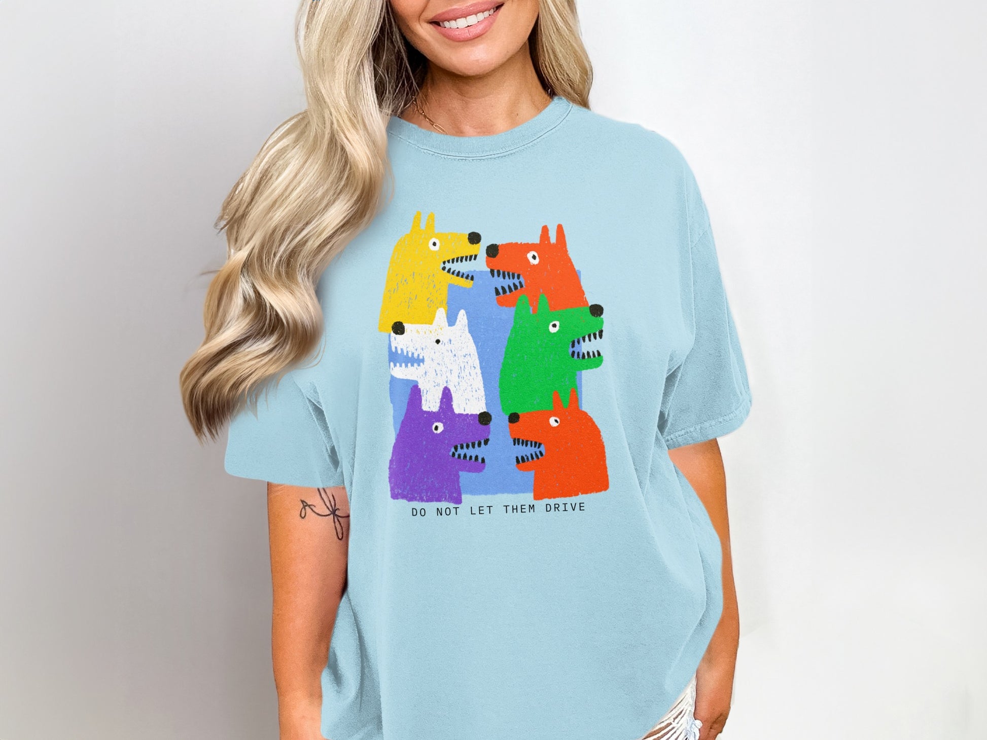 Light blue t-shirt with colorful cartoon dogs saying "DO NOT LET THEM DRIVE".