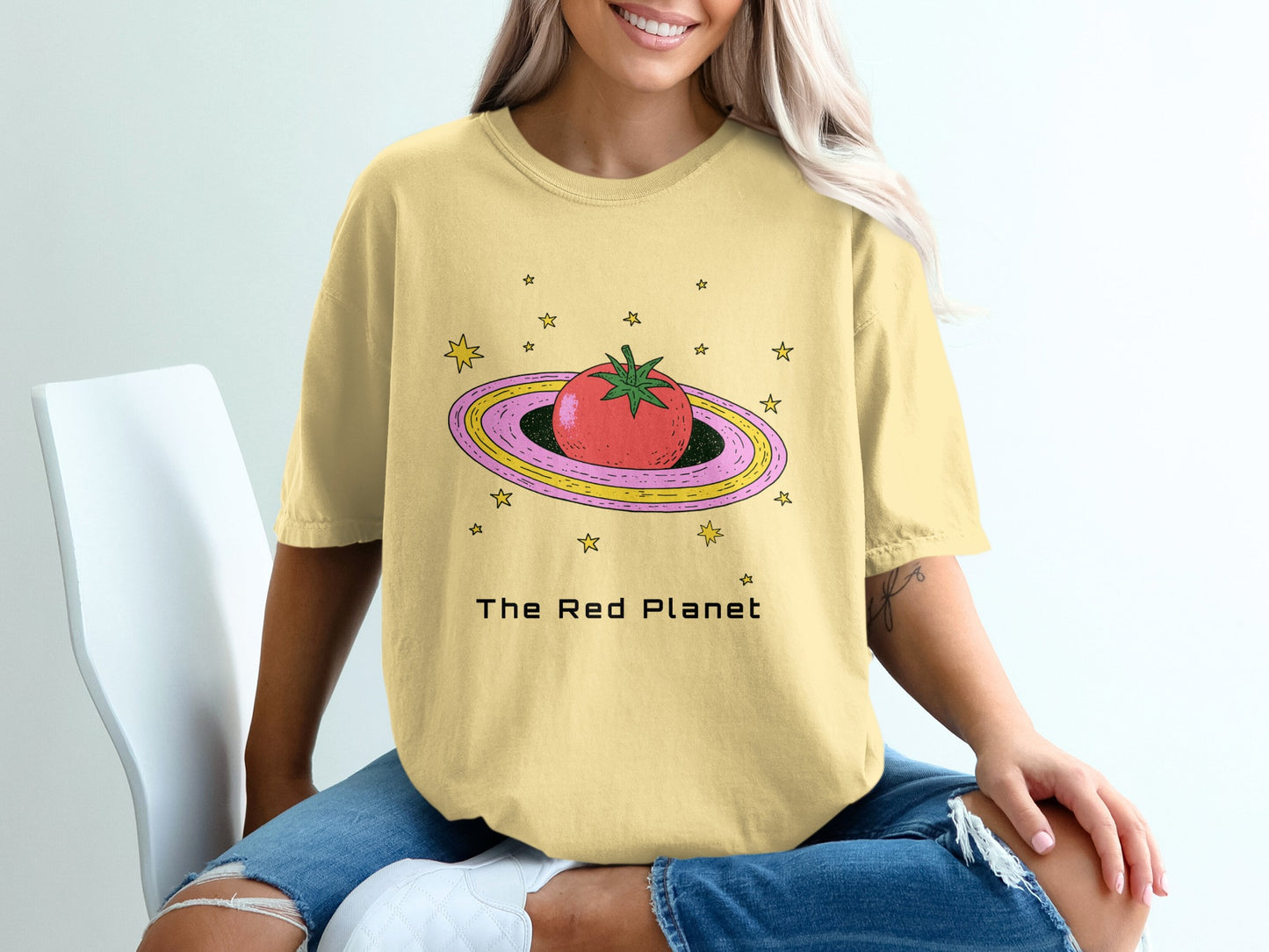 Yellow t-shirt with a tomato and stars on a ringed planet.