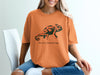 Orange t-shirt with a black chameleon design and "Social Camouflage" text.