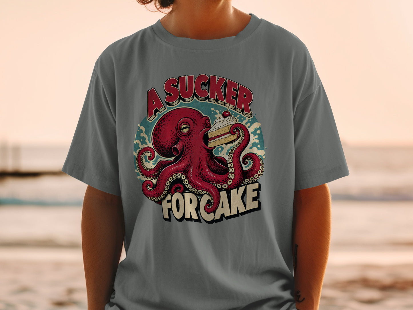 Graphic t-shirt with red octopus holding slice of cake, text "A Sucker For Cake".