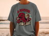 Graphic t-shirt with red octopus holding slice of cake, text "A Sucker For Cake".