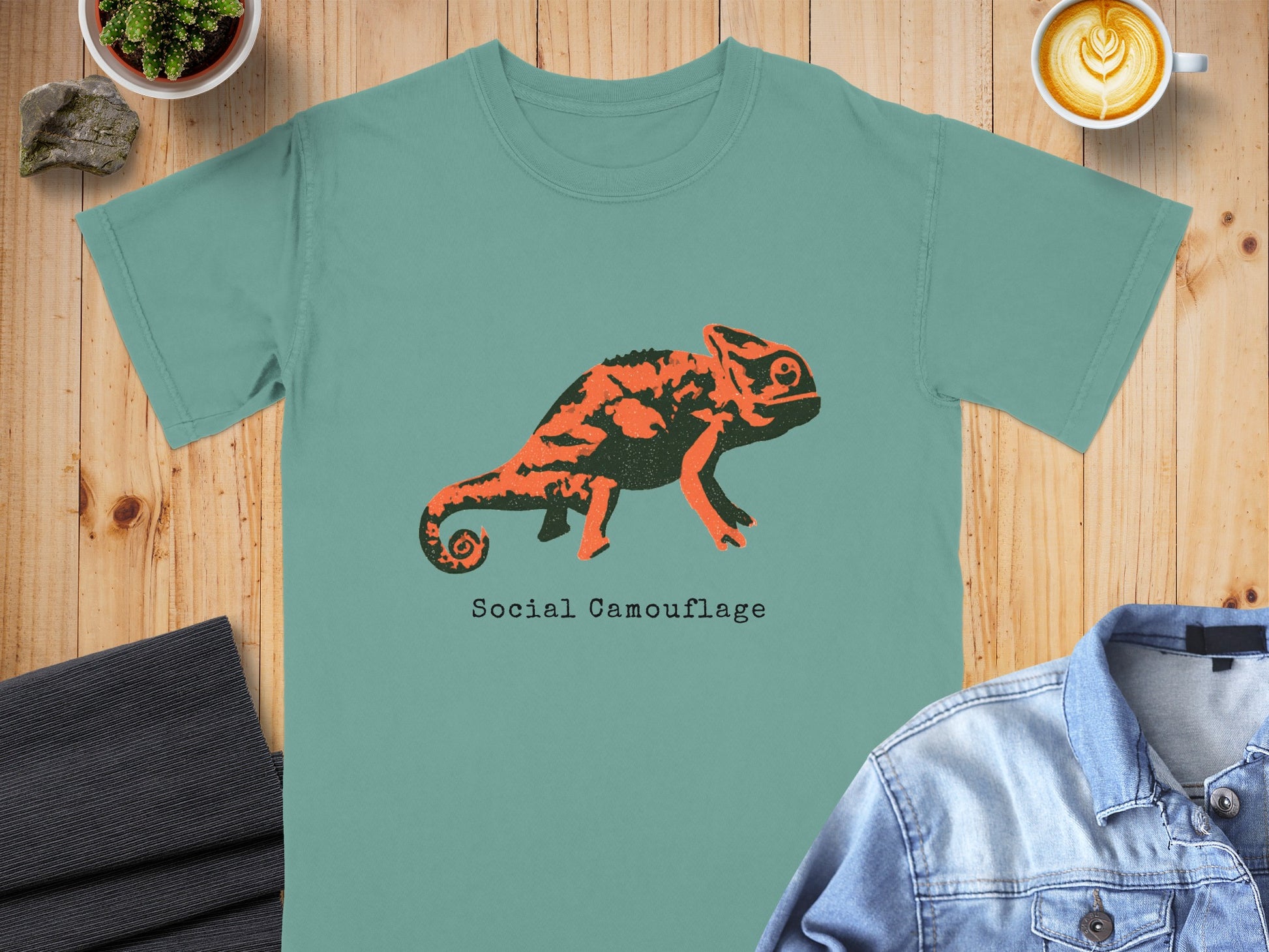 Teal t-shirt with orange chameleon graphic and "Social Camouflage" text.
