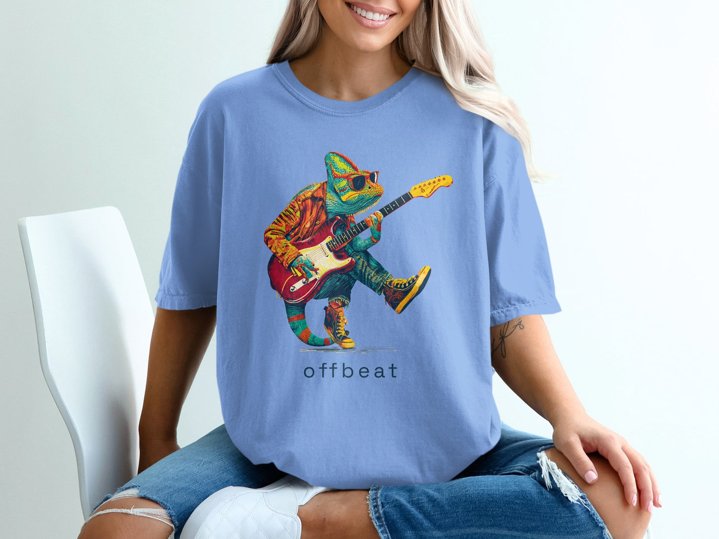 Chameleon wearing sunglasses playing a guitar on a blue t-shirt.