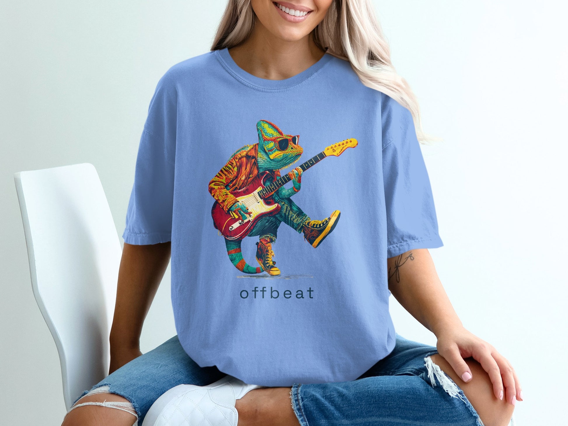 Chameleon wearing sunglasses playing a guitar on a blue t-shirt.